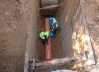 Miasto przeznaczyło prawie 100 mln zł na projekty związane z infrastrukturą kanalizacyjną na zdjęciu widać dwóch robotników, którzy w głębokim dole układają rurę kanalizacyjną