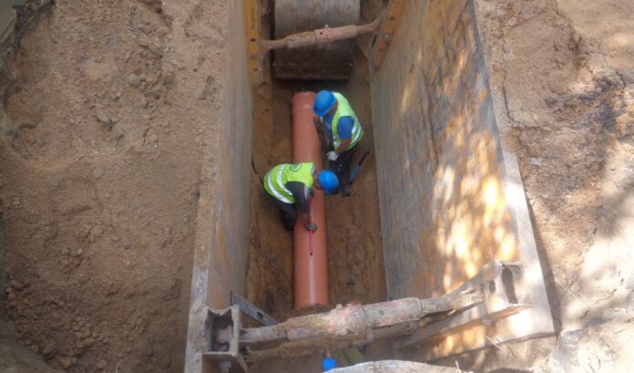 Budowa kanalizacji na os. Zimowym_fot. KAW na zdjęciu widać dwóch robotników, którzy w głębokim dole układają rurę kanalizacyjną