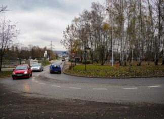 Pięć firm chce zaprojektować przedłużenie ulicy Bocheńskiego w Katowicach na zdjęciu widać zakręt drogi, w miejscu gdzie ulica Bocheńskiego łączy się z il. Załęska Hałda. Po ulicy w obie strony jedzie po kilka samochodów.