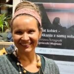 Niezwykła wystawa na wydziale prawa Uniwersytetu Śląskiego na zdjęciu widać autorkę zdjęć Agnieszkę Majnusz, która uśmiechnięta stoi obok plakatu promującego wystawę