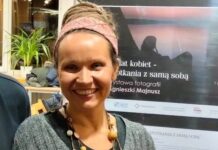 Niezwykła wystawa na wydziale prawa Uniwersytetu Śląskiego na zdjęciu widać autorkę zdjęć Agnieszkę Majnusz, która uśmiechnięta stoi obok plakatu promującego wystawę