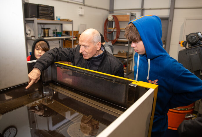 Mężczyzna pokazuje funkcjonowanie maszyny chłopakowi ubranemu w bluzę z kapturem