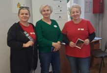 Masz Głos łączy. Żywe Książki z Katowic odwiedziły Kluczbork Trzy uśmiechnięte kobiety stoją w pokoju. Za nimi biała tablica.