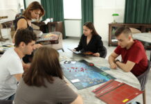 Międzypokoleniowy Planszofest po raz pierwszy w Polsce Ludzie przy stole na którym są gry planszowe