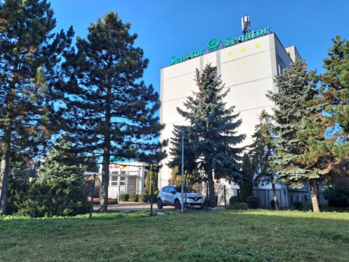 1521694a-b284-40c7-965e-2df5d68e4a0c Hotel a przed nim drzewa