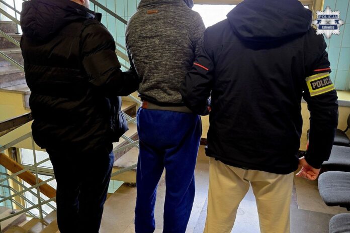 Zatrzymany mężczyzna prowadzony przez dwóch policjantów