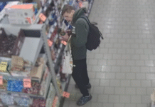 Złodziej z Katowic na nagraniu. Rozpoznajecie go? mężczyzna w kapturze z czarnym plecakiem koło pułki sklepowej