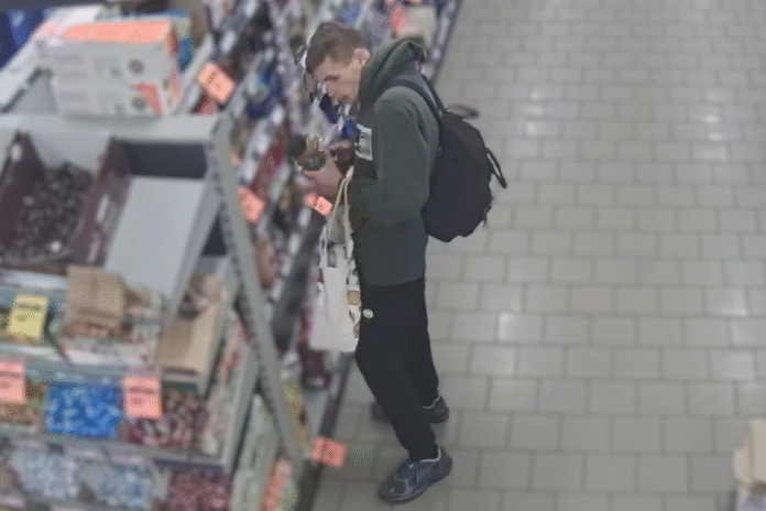 mężczyzna w kapturze z czarnym plecakiem koło pułki sklepowej