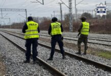 Dramat na torach przerwany w ostatniej chwili Trzech funkcjonariuszy – policjant, strażnik SOK i żołnierz WOT – patroluje tory kolejowe w terenie otwartym.