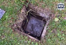 Katowicka policja rozwiązała zbrodnię sprzed lat. W tle kibole i handel narkotykami Otwarty fragment ziemi z wykopanym dołem, w którym widoczna jest przykryta błotem płyta lub pokrywa, otoczona trawą.